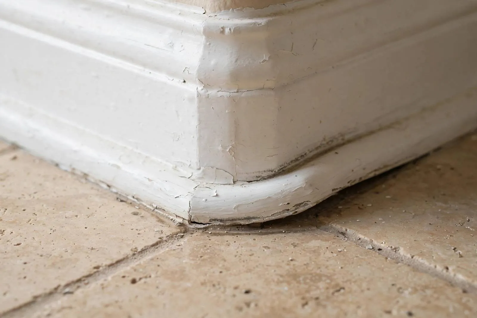 Damaged baseboard with moisture staining at floor level in a home